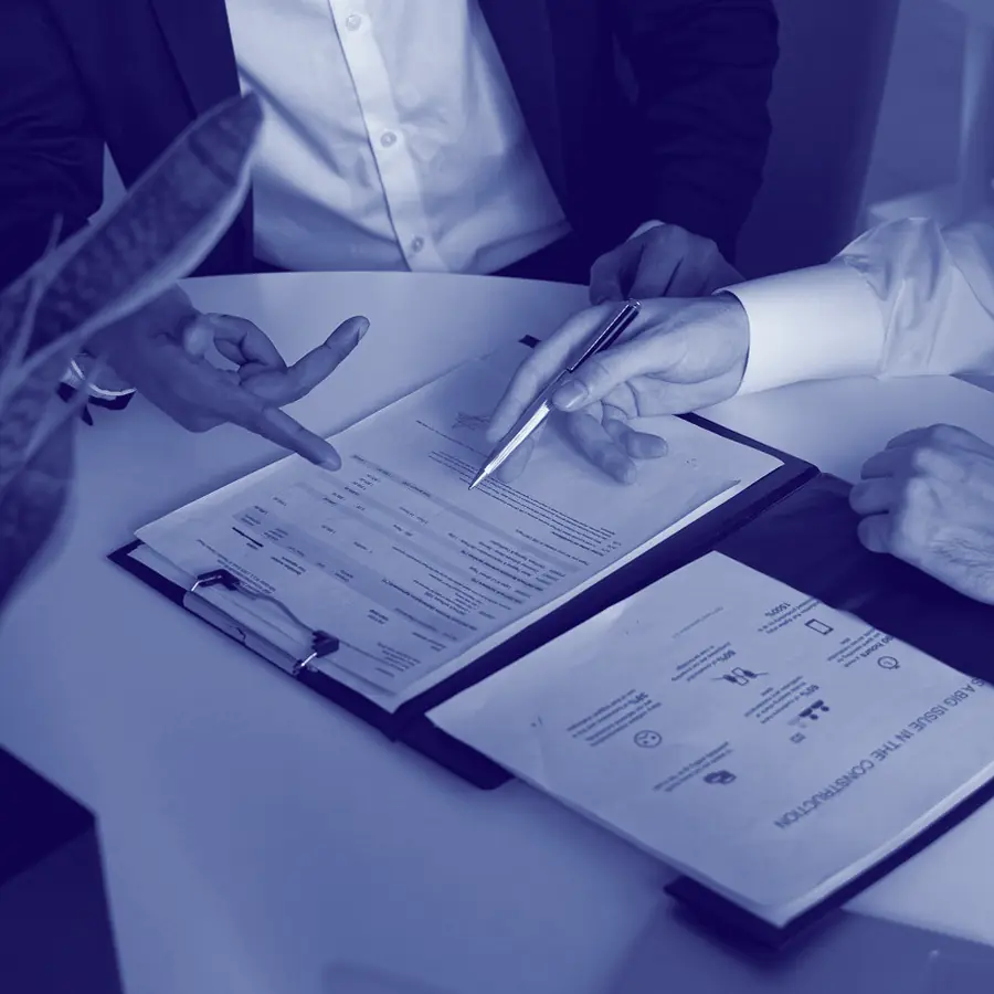 Two people going through papers at a table, one pointing with a pen